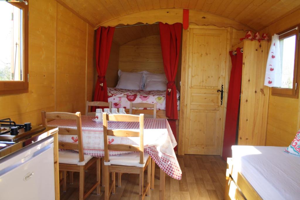 une chambre avec un lit, une table et des chaises dans l'établissement Roulotte Poulette, à Mortagne-au-Perche