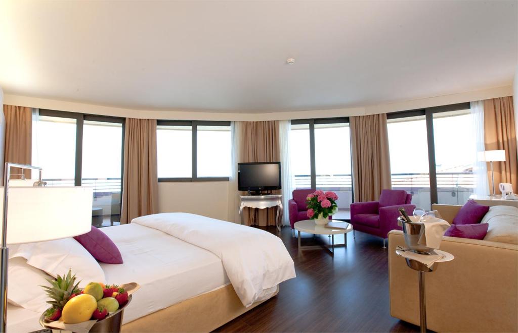 une chambre avec un grand lit et un salon dans l'établissement Laguna Palace Hotel Grado, à Grado