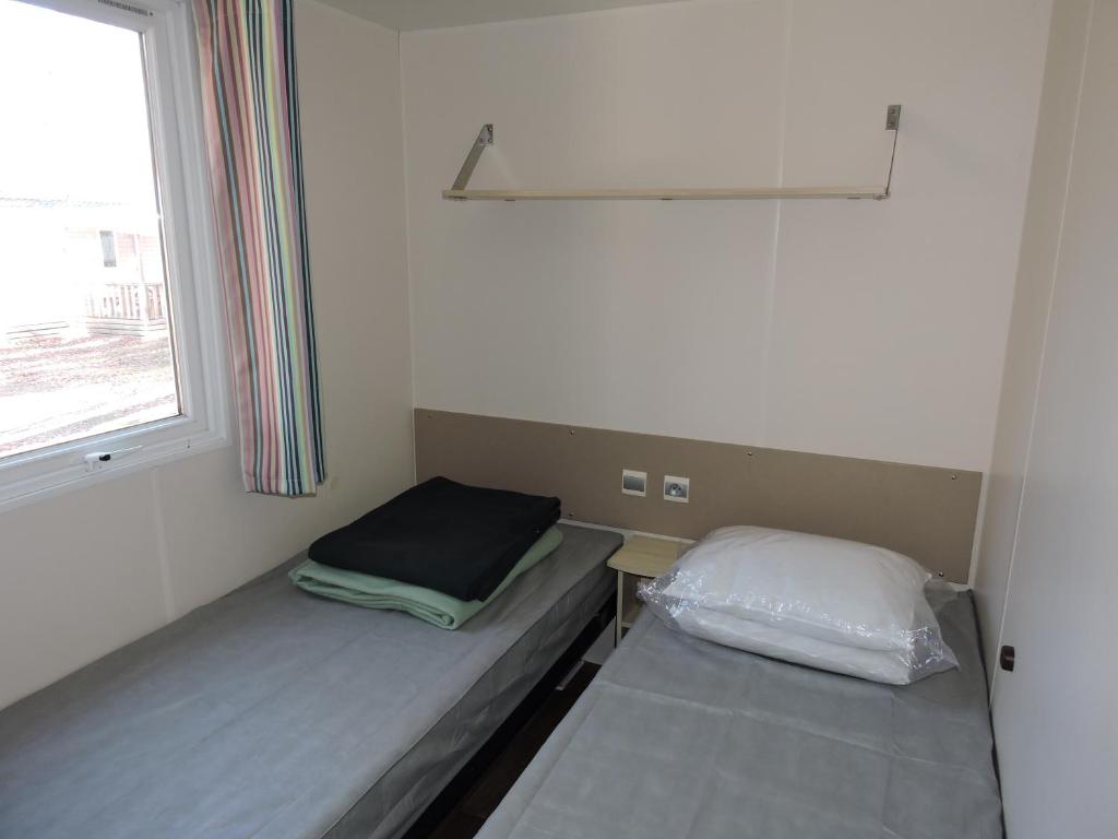 une petite chambre avec deux lits et une fenêtre dans l'établissement Mobil-Home climatisé 6p Lac de Mimizan-Aureilhan Rivages des Landes 4 étoiles, à Aureilhan 32 autres photos