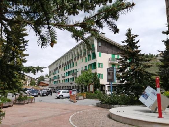 un grand bâtiment avec des voitures garées dans un parking dans l'établissement Central Park Grand 2 Pieces centre Valberg, à Valberg