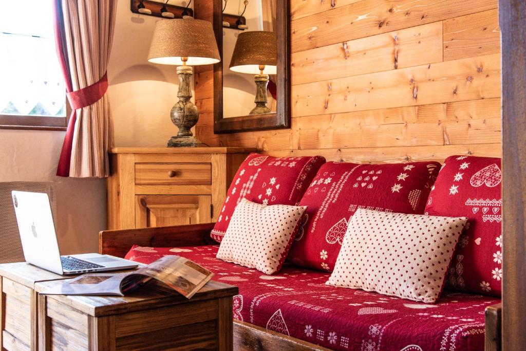 - un canapé rouge avec des oreillers et un ordinateur portable sur une table dans l'établissement Club Alpina - Champagny-en-Vanoise, à Champagny-en-Vanoise