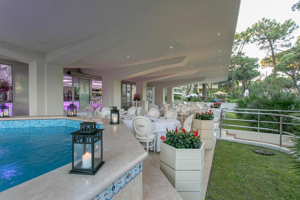 - une piscine avec une table et des chaises à côté de la piscine dans l'établissement Boutique Hotel Paradiso Bovelacci, à Milano Marittima