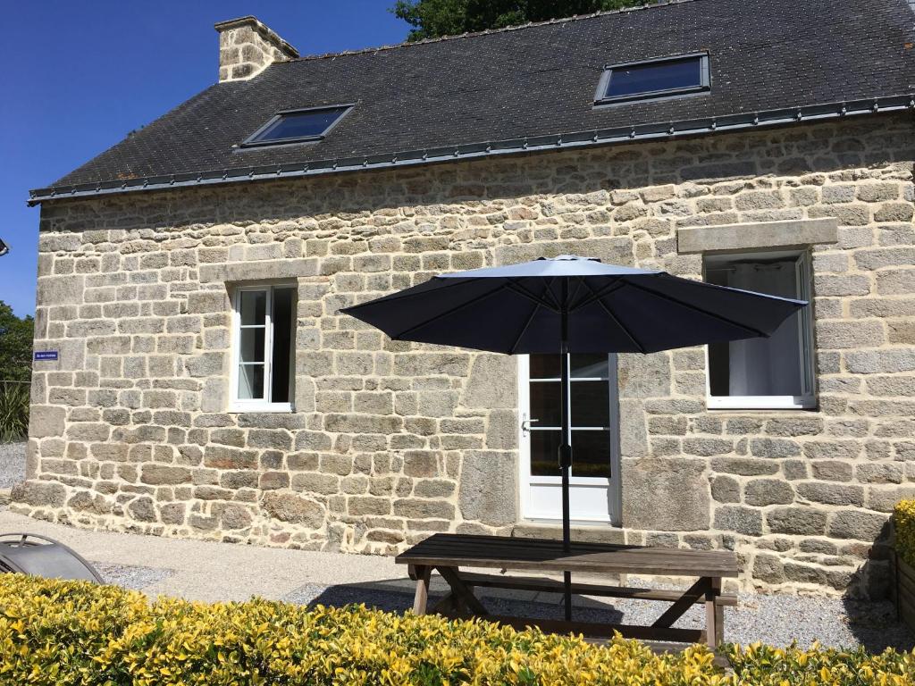 - une table de pique-nique avec un parasol devant le bâtiment dans l'établissement Gite de kermoel, ile aux moines, à Saint-Caradec-Trégomel