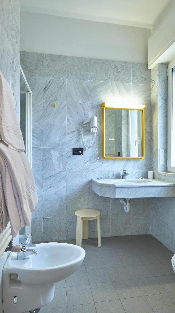 une salle de bain blanche avec un lavabo et un miroir dans l'établissement Hotel Adler, à Alassio