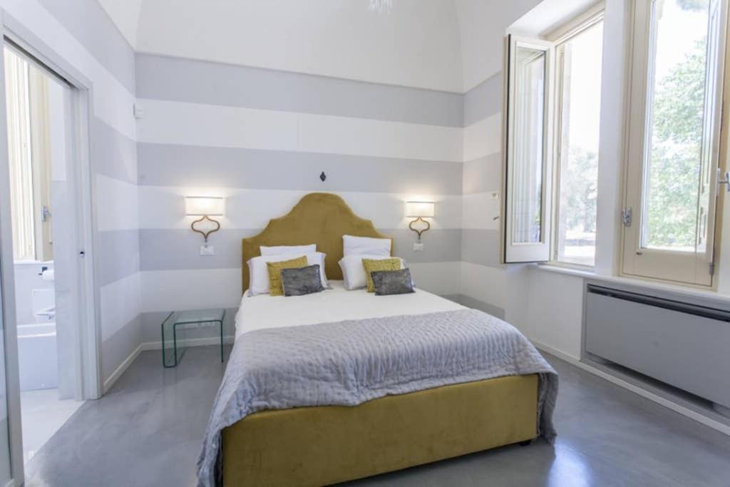 une chambre avec un grand lit avec deux fenêtres dans l'établissement Villa Fontana, à Francavilla Fontana 119 autres photos