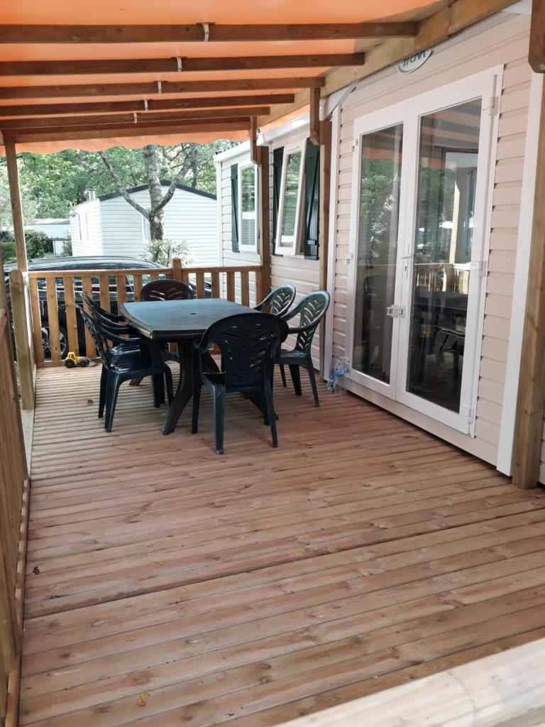 un patio avec une table et des chaises sur une terrasse dans l'établissement Mobil-Home climatisé 6p Lac de Mimizan-Aureilhan Rivages des Landes 4 étoiles, à Aureilhan