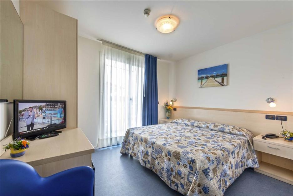 une chambre d'hôtel avec un lit et une télévision dans l'établissement Hotel Minerva, à Lignano Sabbiadoro