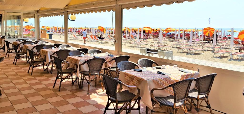 un restaurant avec des tables et des chaises ainsi qu'une plage dans l'établissement Hotel Righetto Fronte Mare, à Cavallino-Treporti