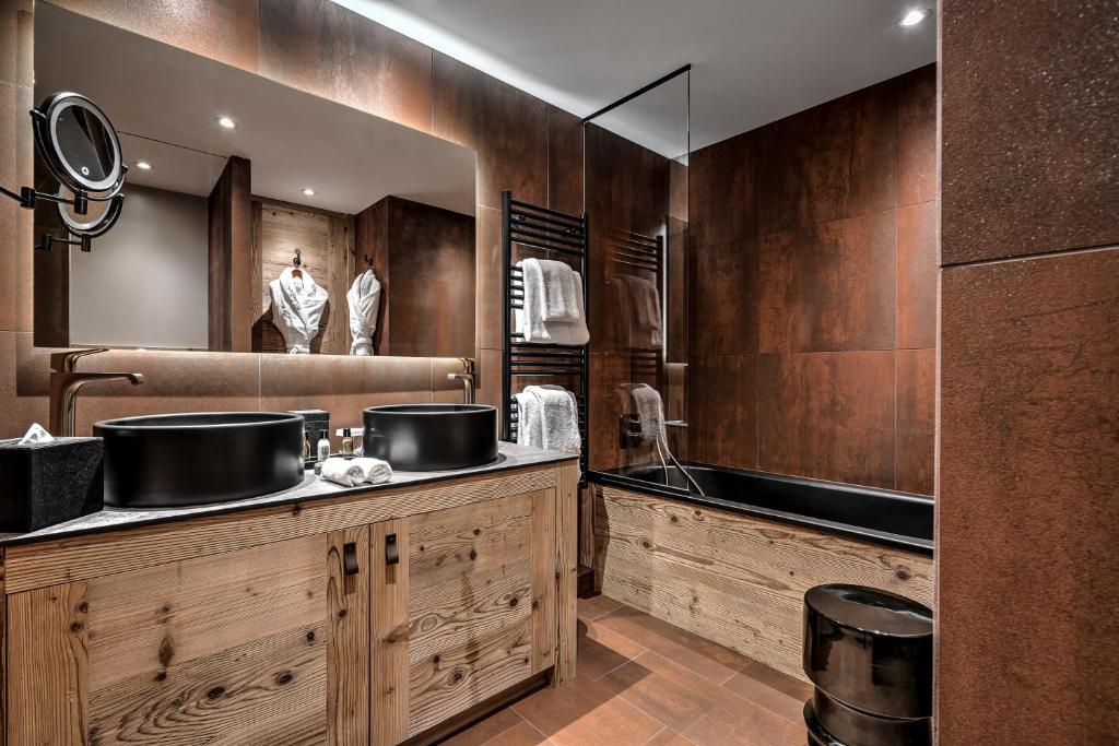 une salle de bain avec deux lavabos et un grand miroir dans l'établissement Hôtel La Sivolière, à Courchevel