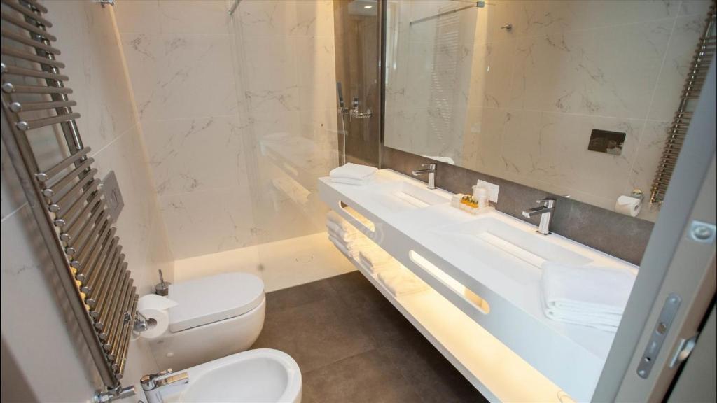 une salle de bain avec toilettes, lavabo et miroir dans l'établissement Hotel Principe Palace, à Lido di Jesolo