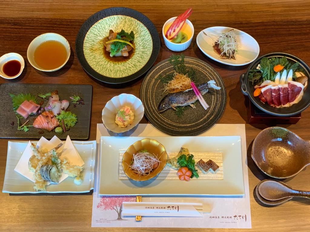 une table en bois avec des assiettes de nourriture dessus dans l'établissement Ikeda Onsen Ryokan Tachikawa, à Ōgaki