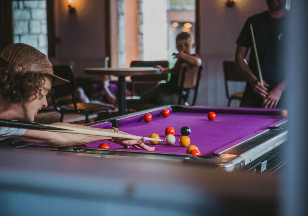 un homme jouant au billard avec des balles sur un billard dans l'établissement Hôtel Les Grangettes, à Méribel