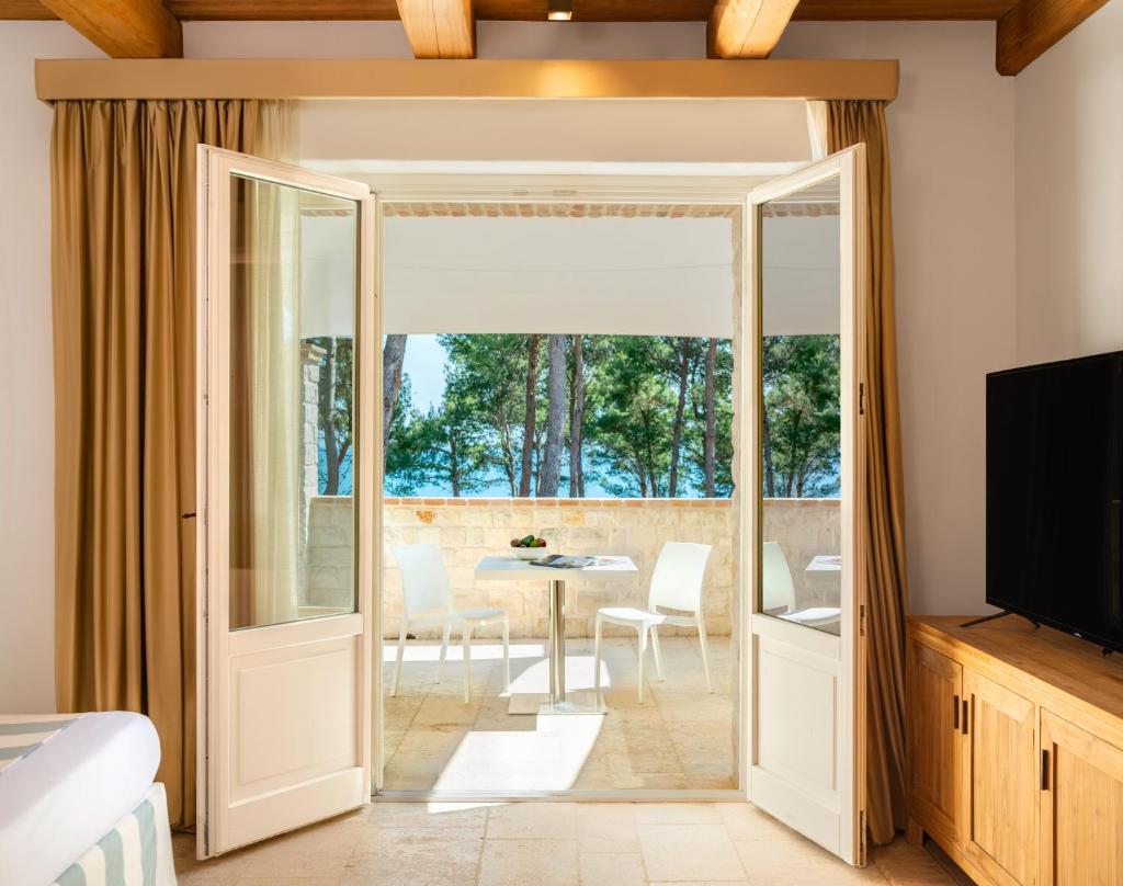 Cette chambre dispose d'une porte s'ouvrant sur une terrasse avec une table. dans l'établissement San Michele Relais & Spa, à Sirolo