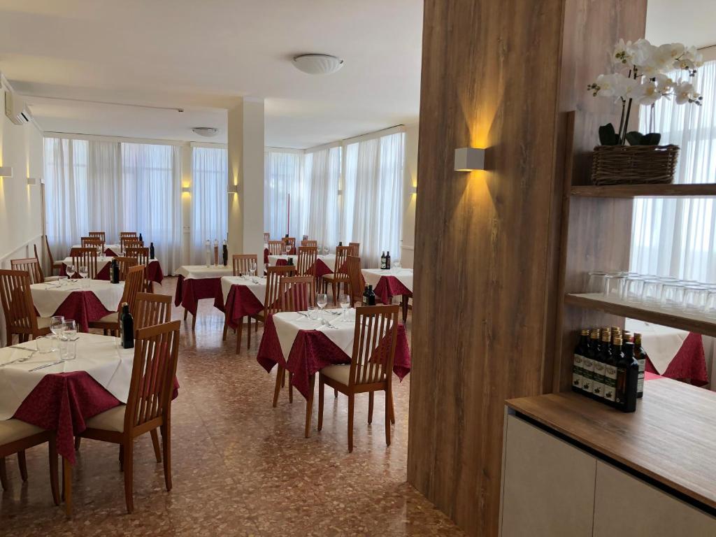 une salle à manger avec des tables, des chaises et des serviettes rouges dans l'établissement Hotel Karibe, à Bibione