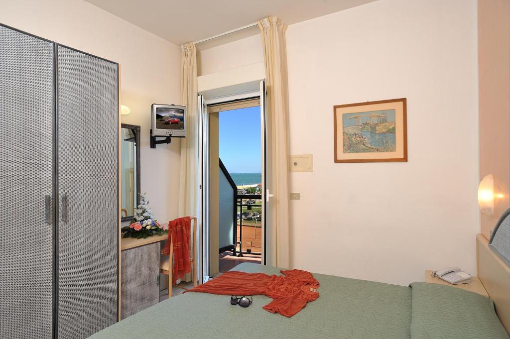 une chambre avec un lit et une porte coulissante en verre dans l'établissement Hotel Ausonia, à Milano Marittima