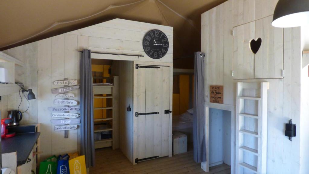 une chambre avec une horloge sur le mur et une porte dans l'établissement La tente de la plage, à Plouha