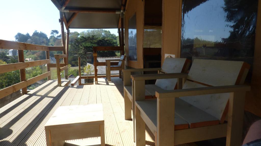 une véranda avec des chaises et une fenêtre sur un bâtiment dans l'établissement La tente de la plage, à Plouha