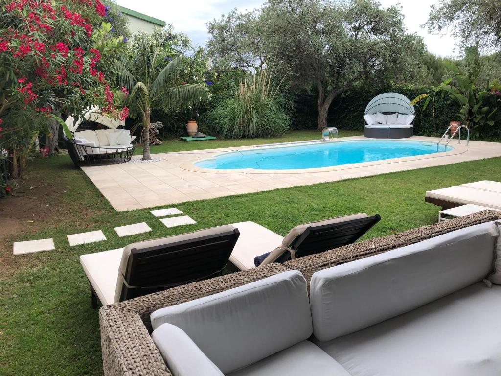 une cour avec une piscine dotée de 2 chaises longues et une piscine dans l'établissement Villa Ines con piscina sud Sardegna, à Capoterra
