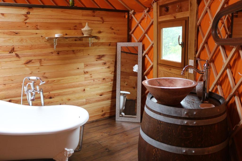 La salle de bains est pourvue d'une baignoire et d'un lavabo dans une cabine. dans l'établissement yourtes coccinelles, à Conchez-de-Béarn
