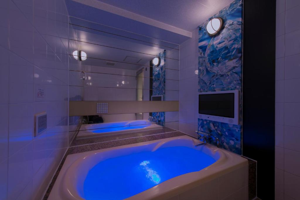 une salle de bain avec une grande baignoire bleue avec une télévision dans l'établissement Hotel Eldia Machida -Adult Only, à Kami-seya