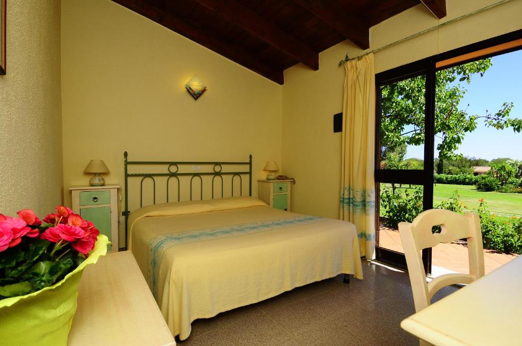 une chambre avec un lit, une table et une fenêtre dans l'établissement Hotel L'Esagono, à San Teodoro