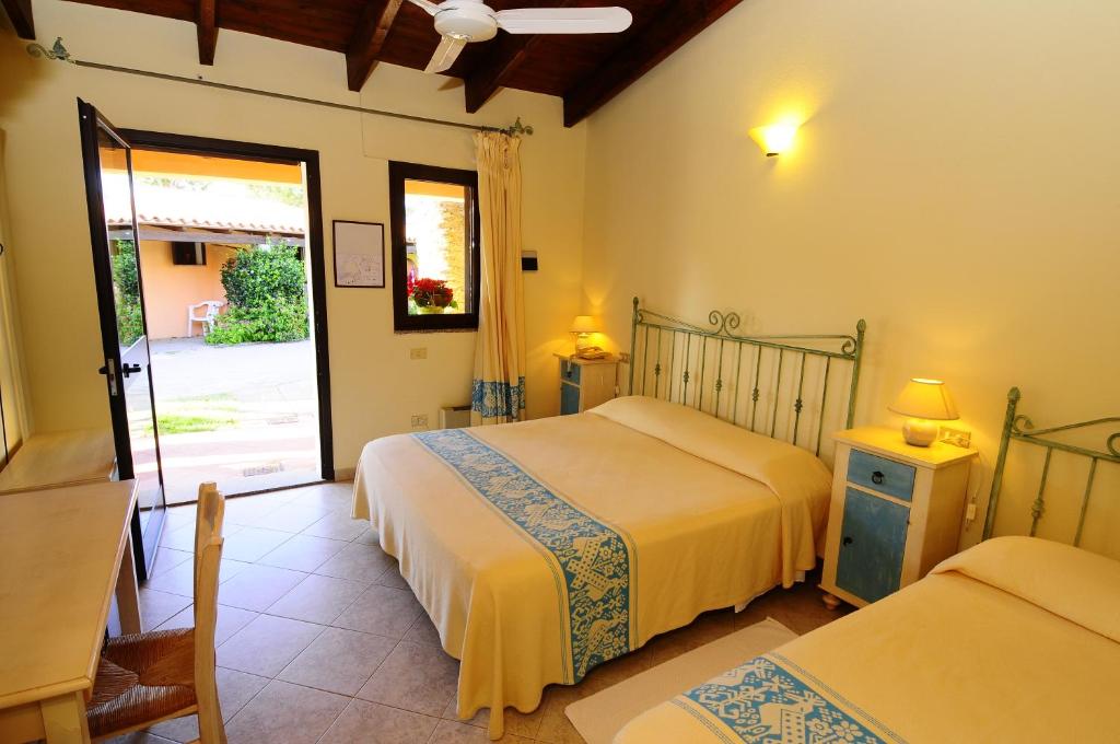 - une chambre avec 2 lits et une porte coulissante en verre dans l'établissement Hotel L'Esagono, à San Teodoro 70 autres photos