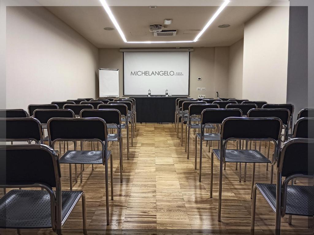 une salle de conférence avec des chaises et un écran dans l'établissement Hotel Michelangelo, à Carrara