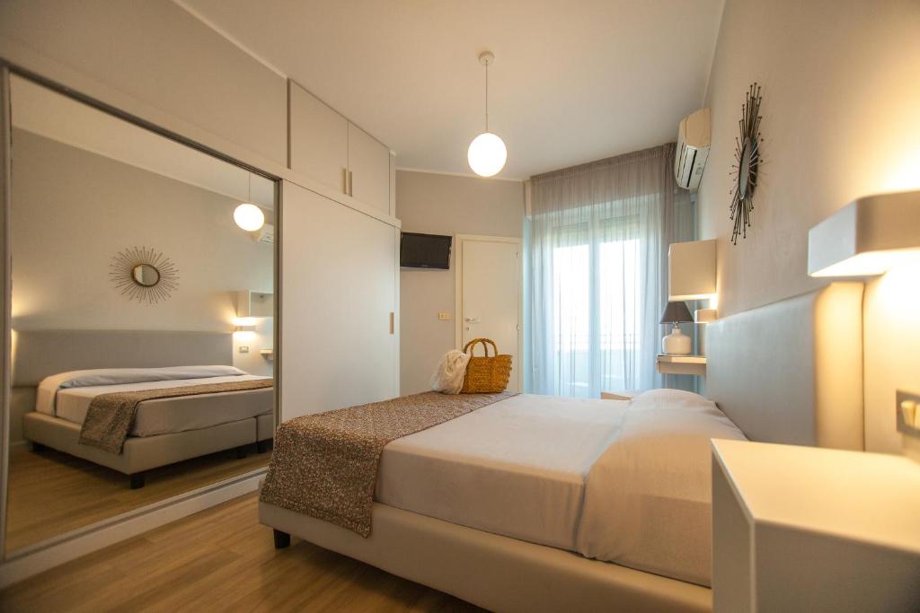 une chambre d'hôtel avec deux lits et un miroir dans l'établissement Hotel Brig, à Riccione
