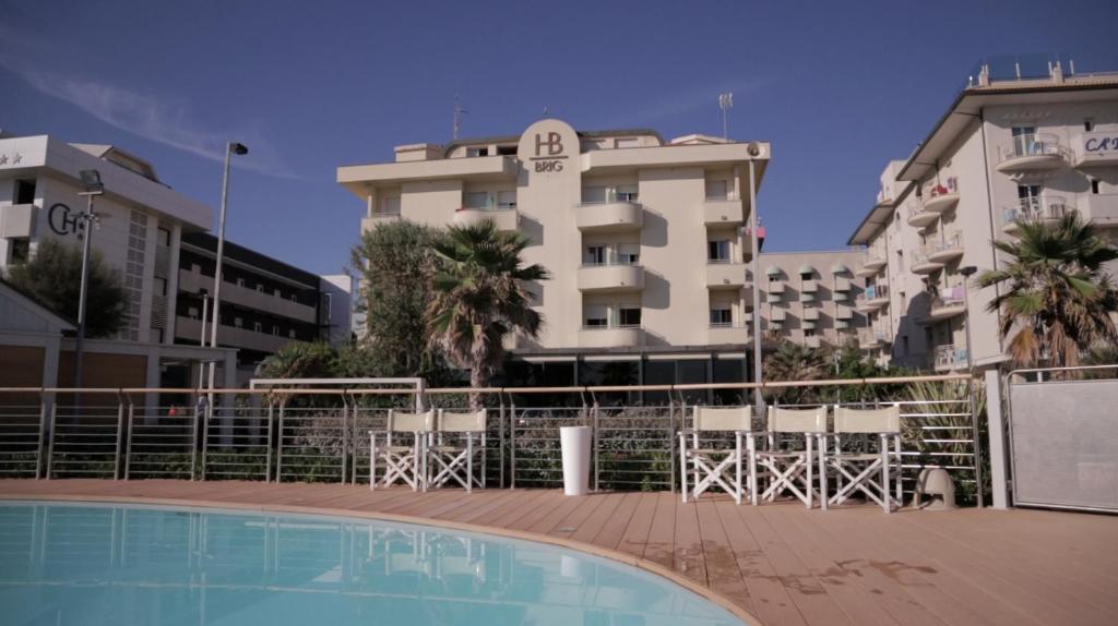 un hôtel avec une piscine devant un bâtiment dans l'établissement Hotel Brig, à Riccione