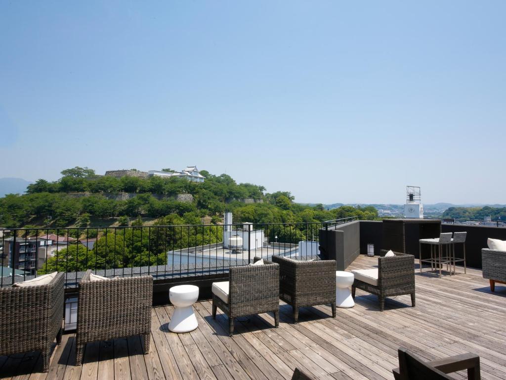 un patio avec des chaises et des tables sur un toit dans l'établissement The Shiroyama Terrace Tsuyama Villa, à Tuyama