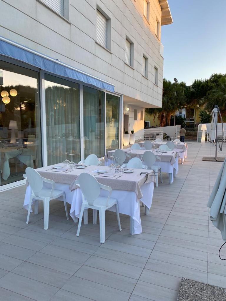 - une rangée de tables et de chaises blanches sur la terrasse dans l'établissement Elite Boutique Hotel, à Roseto degli Abruzzi