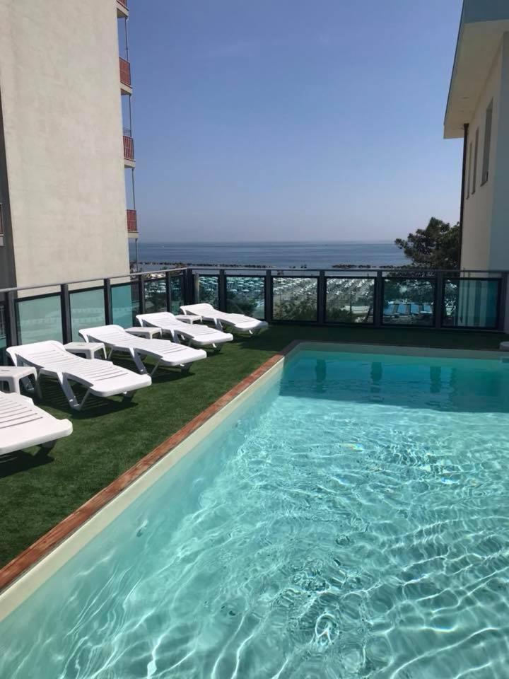 - une piscine avec des chaises longues et des chaises dans un bâtiment dans l'établissement Hotel Mirage, à Lido di Classe