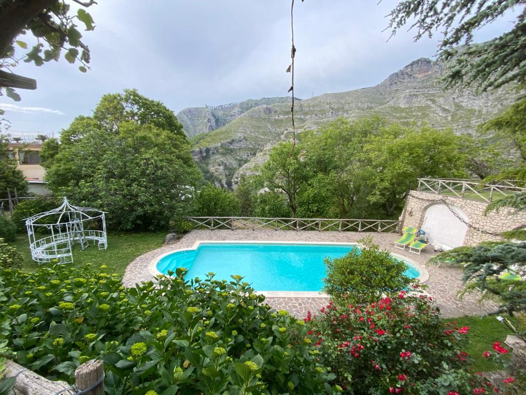 une piscine dans un jardin avec des montagnes en arrière-plan dans l'établissement Rocca Angelica, à Vico Equense