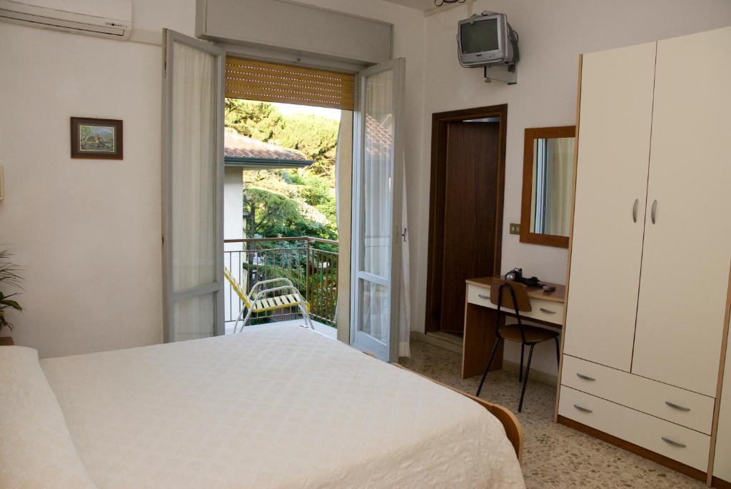 une chambre avec un lit et un bureau et un balcon dans l'établissement Hotel Carezza, à Cervia