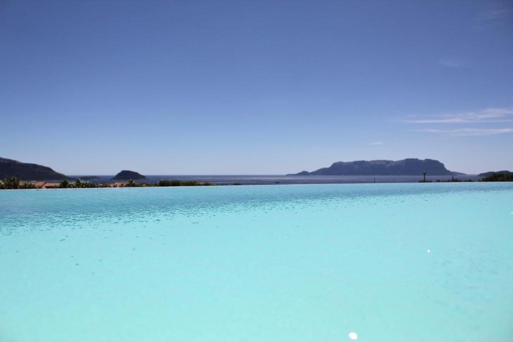 une grande étendue d'eau bleue avec des montagnes en arrière-plan dans l'établissement VILLA ALBA NUOVA with infinity pool & amazing sea view, à Golfo Aranci