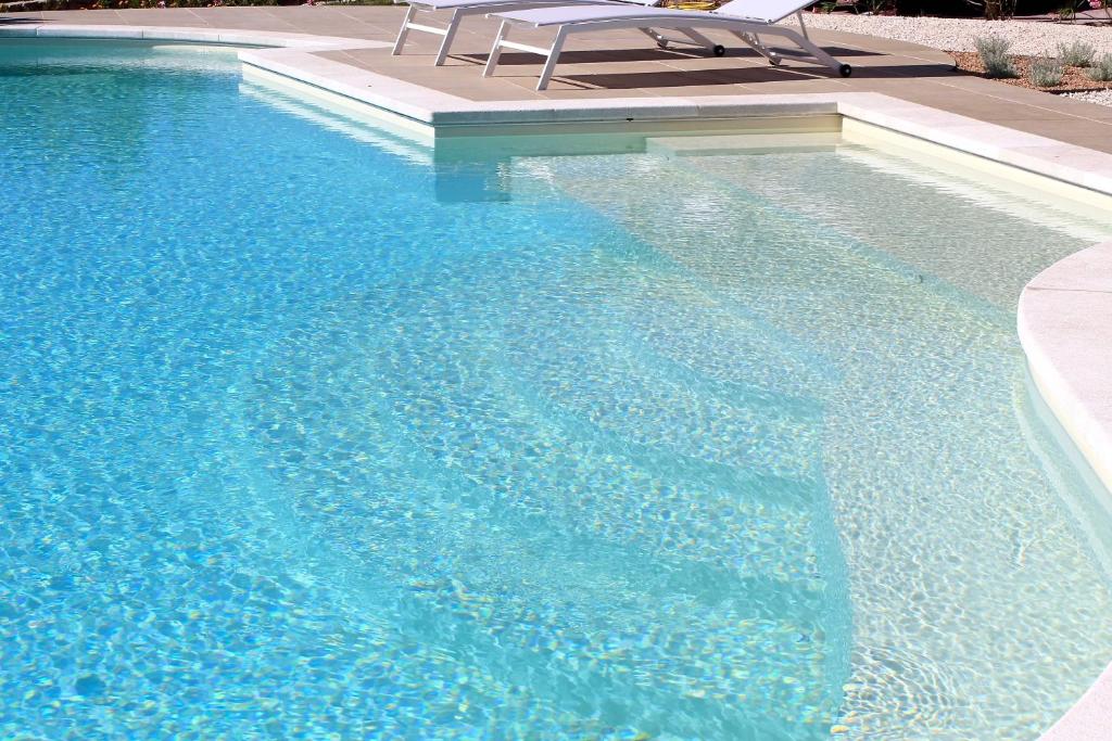 une piscine d'eau bleue avec un banc dedans dans l'établissement VILLA ALBA NUOVA with infinity pool & amazing sea view, à Golfo Aranci