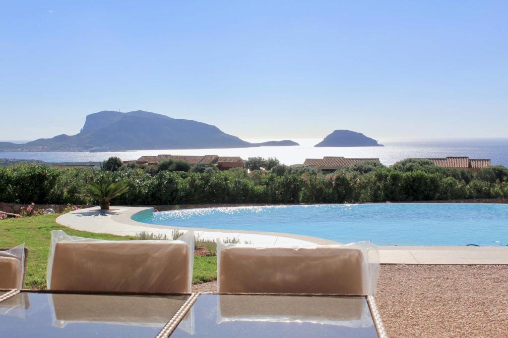 une piscine avec des chaises et l'océan en arrière-plan dans l'établissement VILLA ALBA NUOVA with infinity pool & amazing sea view, à Golfo Aranci