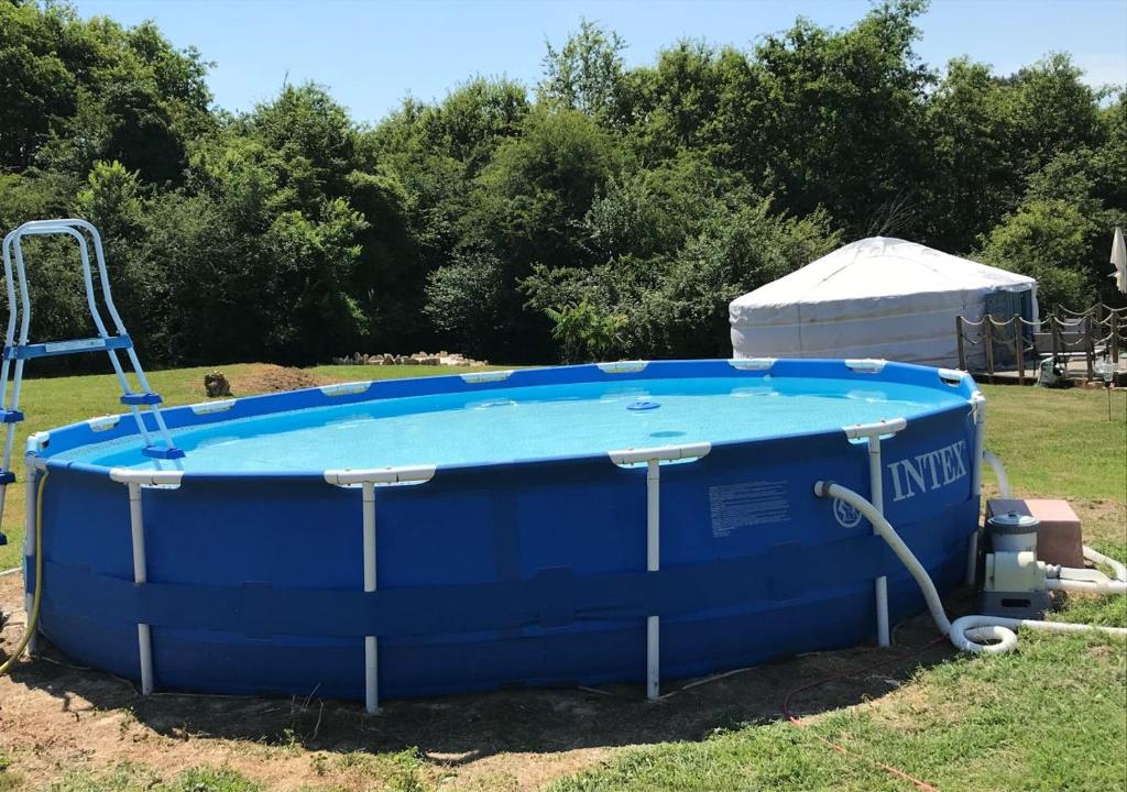une grande piscine bleue assise dans l'herbe dans l'établissement French Fields Luxury Glamping Twin Emperor Tent, à Le-Vieux-Cérier