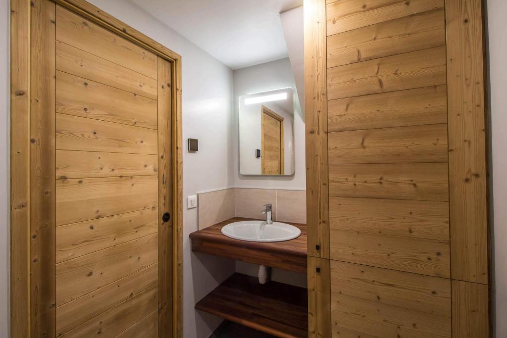 La salle de bains est pourvue d'un lavabo et d'une porte en bois. dans l'établissement 30 Praz Ski-in Ski-out Vallandry - Les Arcs - Paradiski, à Peisey-Nancroix