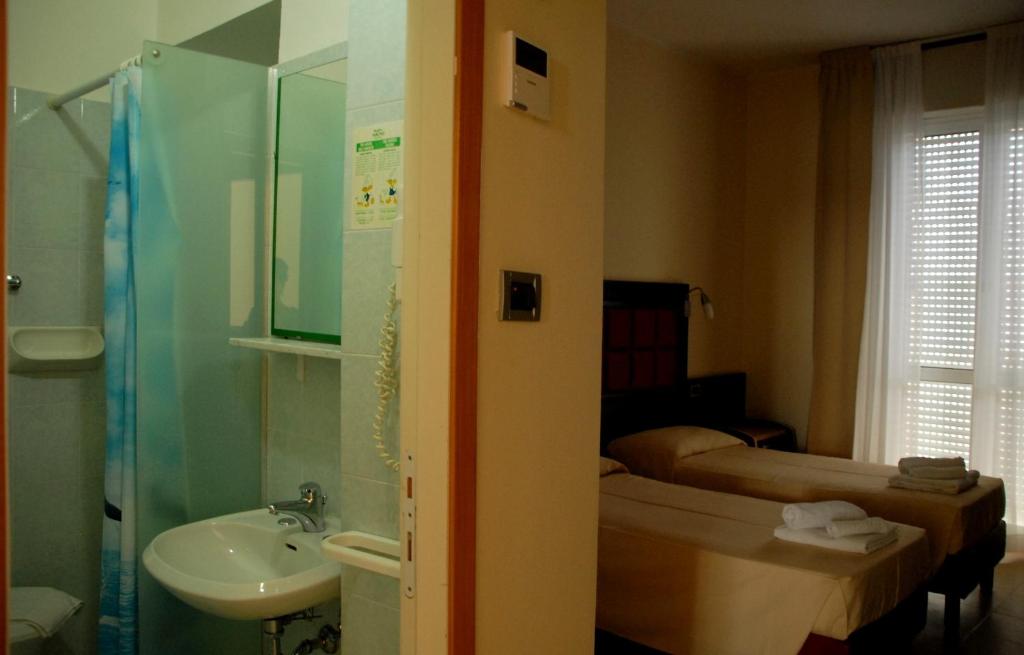 une salle de bain avec un lavabo et des toilettes et un lit dans l'établissement Hotel Arno, à Rimini