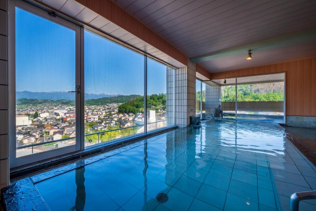 - une piscine intérieure avec vue sur la ville dans l'établissement onsen hotel OMOTO, à Matsumoto