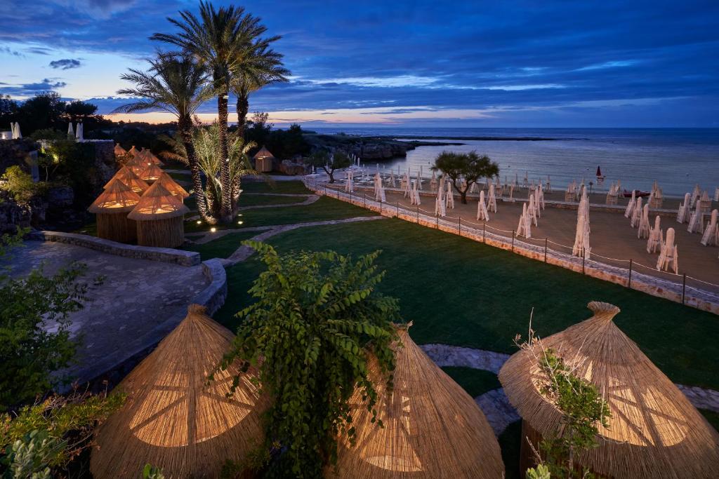 une cérémonie de mariage sur la plage avec des parasols dans l'établissement Grotta Palazzese Beach Hotel, à Polignano a Mare
