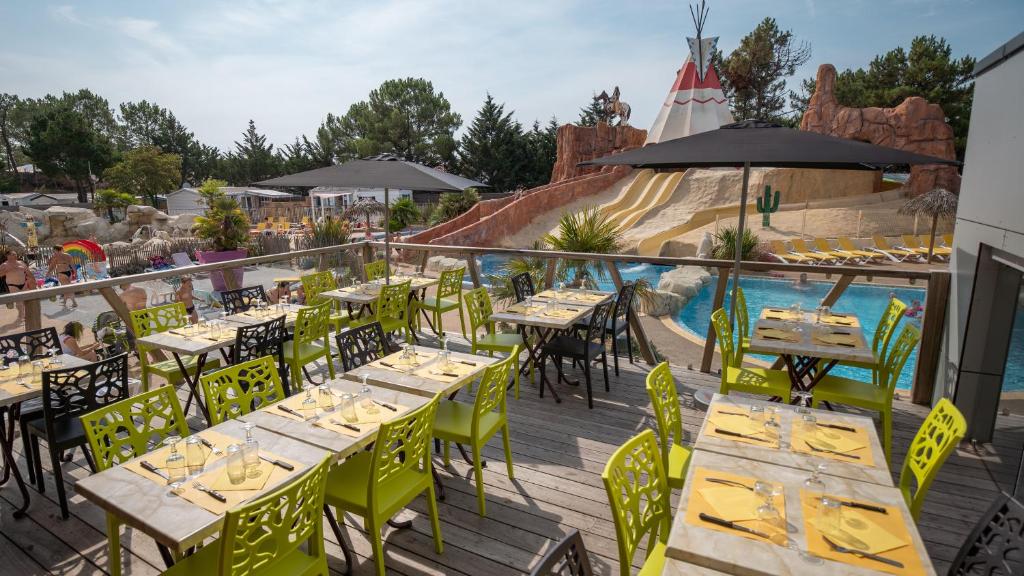 - un coin repas extérieur avec des tables et des chaises ainsi qu'une piscine dans l'établissement Mobile Homes by KelAir at Camping Les Genets, à Saint-Jean-de-Monts