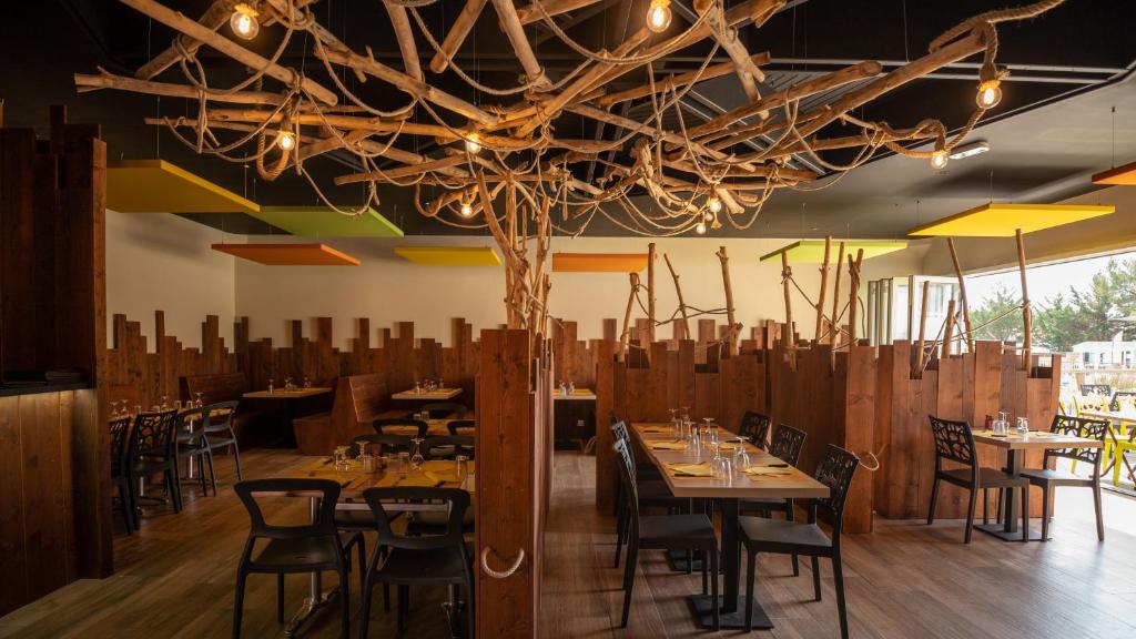 une salle à manger avec des tables et des chaises sous un lustre dans l'établissement Mobile Homes by KelAir at Camping Les Genets, à Saint-Jean-de-Monts