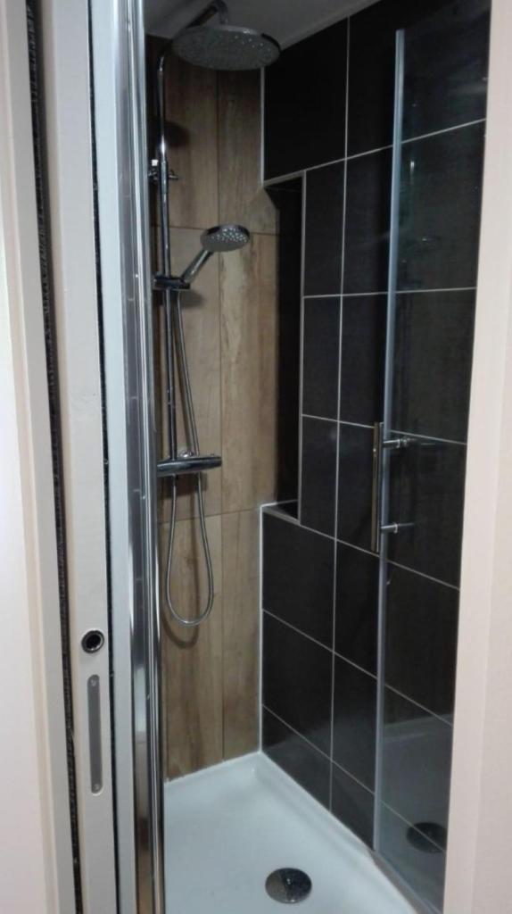 La salle de bains est pourvue d'une douche et de carrelage noir. dans l'établissement Le 67,ski et randonnée,lave linge,sèche linge,wifi,parking gratuit, à Bernex