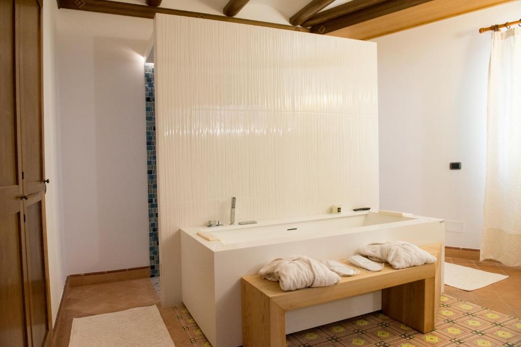 La salle de bains est pourvue d'une baignoire et de serviettes sur un banc. dans l'établissement Taverna Del Capitano, à Massa Lubrense