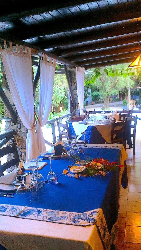Cette chambre comprend une table bleue avec des chaises et des rideaux. dans l'établissement La Francesca Sud un villaggio"glamping", à Scario