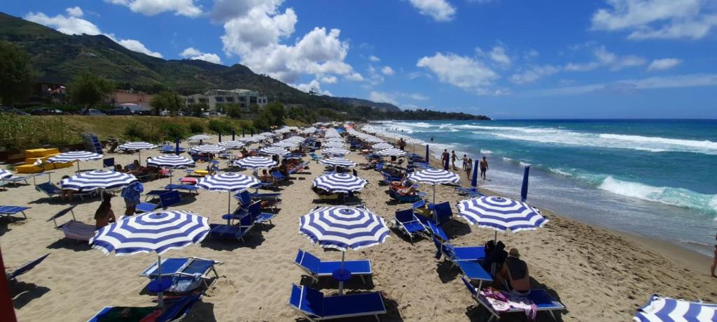 une plage avec des parasols bleus et blancs et l'océan dans l'établissement Villa Gaia Hotel, à Cefalù