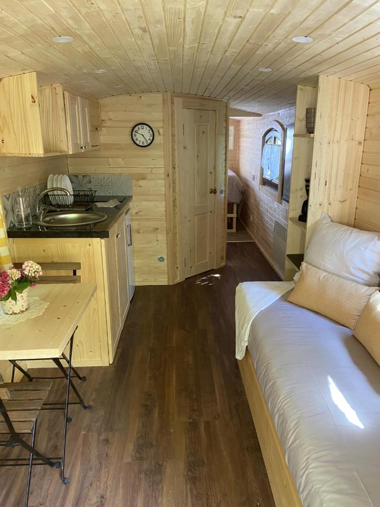 une chambre avec un lit et une cuisine avec une table dans l'établissement La Roulotte d'Emilie et son jacuzzi privé, à Beurlay