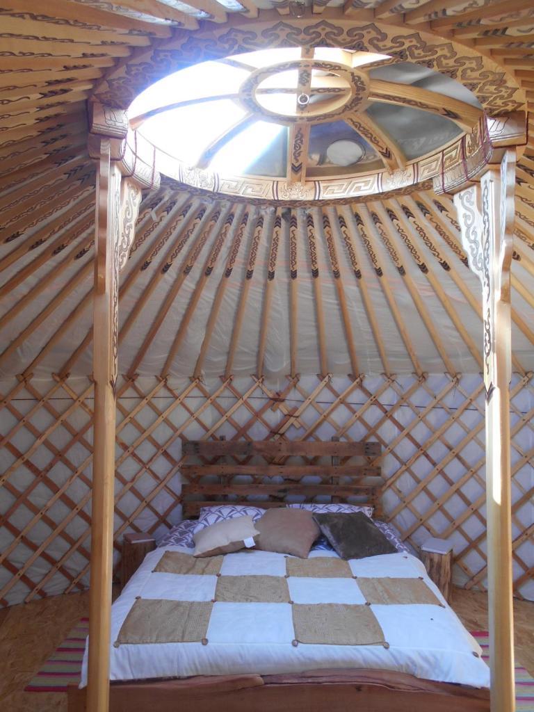 - une chambre avec un lit en bois dans une yourte dans l'établissement 2 Yourtes au naturel, à Druyes-les-Belles-Fontaines